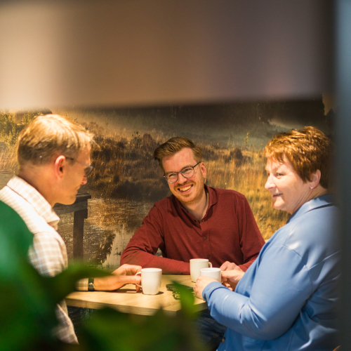Collega's zitten lachend aan tafel in kantine
